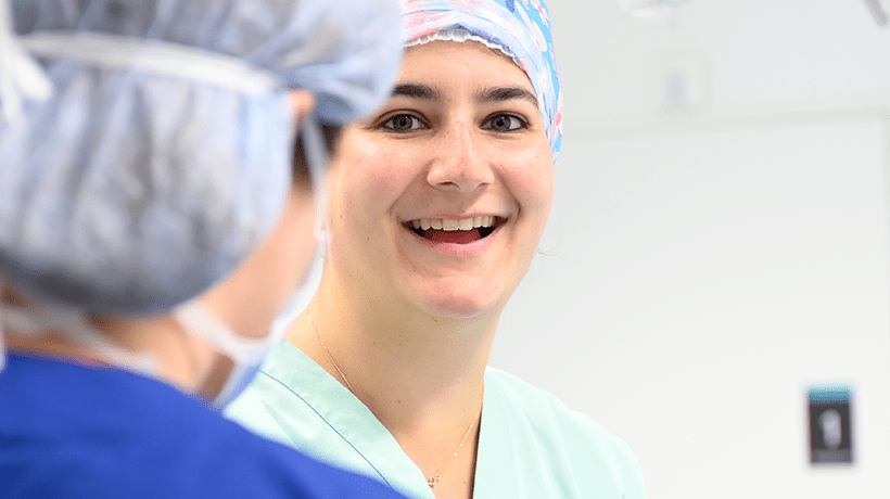 Une soignante de face regarde la caméra en souriant