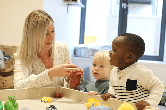 Une auxiliaire joue avec deux enfants en bas âge dans une crèche VYV Enfance