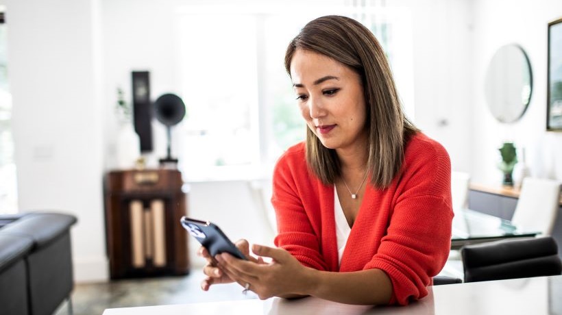 Une jeune femme consulte un portable pour évoquer la question des IA conversationnelles en santé mentale.