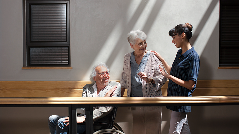 Une jeune femme sourit à un couple de personnes âgées, dans un établissement de la MF Charente
