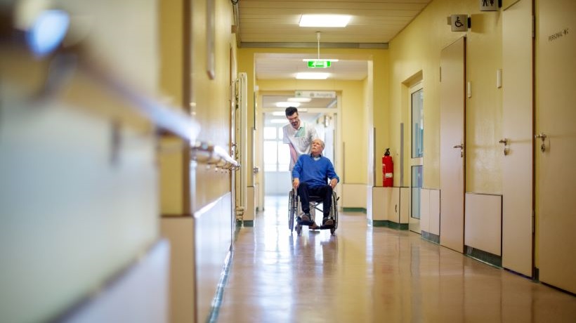Une infirmière pousse une personne dans un fauteuil pour illustrer les déserts médicaux